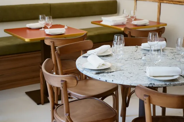 Comedor con bancos verdes y mesas de terrazo